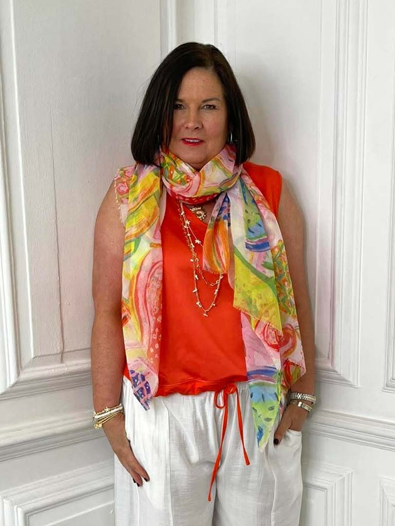 Colorful fruit-print scarf in orange and pink draped over sleeveless orange top, styled for womens fashion and relaxed. - Malissa J Fruit Scarf - Orange