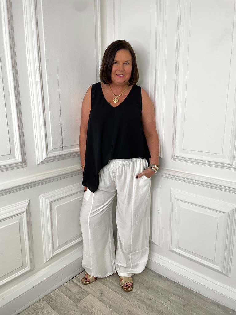 White wide curved hem trousers paired with black sleeveless top, relaxed styling for everyday wear in womens fashion. - Wide Curved Hem Trousers - White