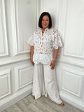 White broderie anglaise blouse with short puff sleeves and scalloped hem paired with wide-leg cream trousers for relaxed. - Malissa J Luxe Broderie Anglaise Top